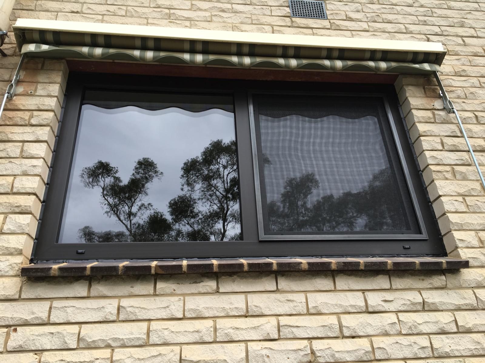 Black uPVC sliding window on textured brickwork