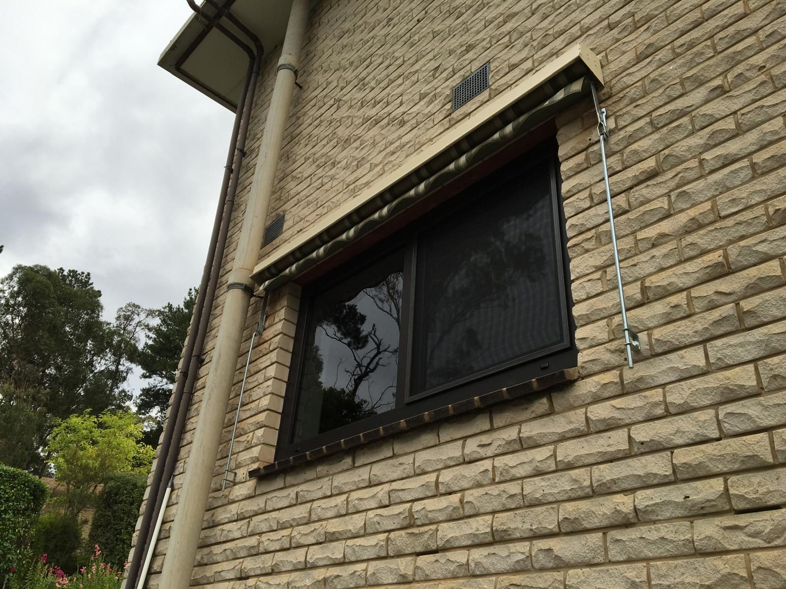 Black uPVC awning window on a rendered brick wall