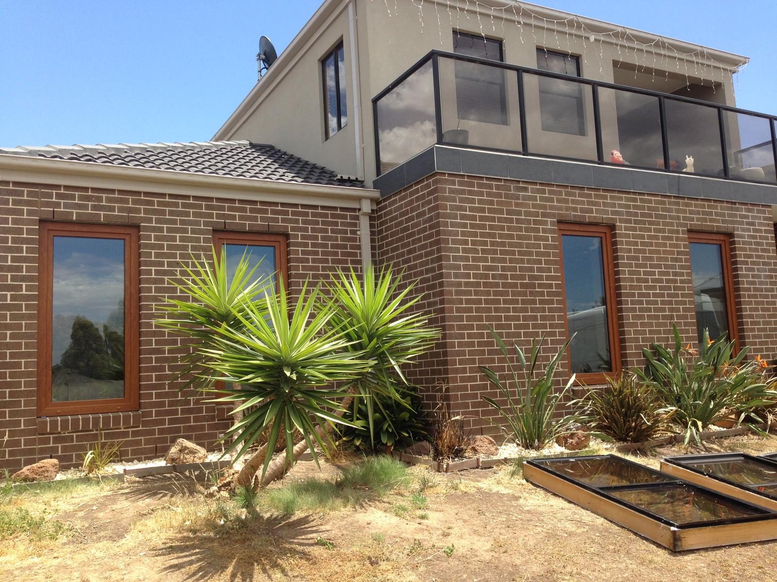 Dark double glazed windows on a two storey brick home
