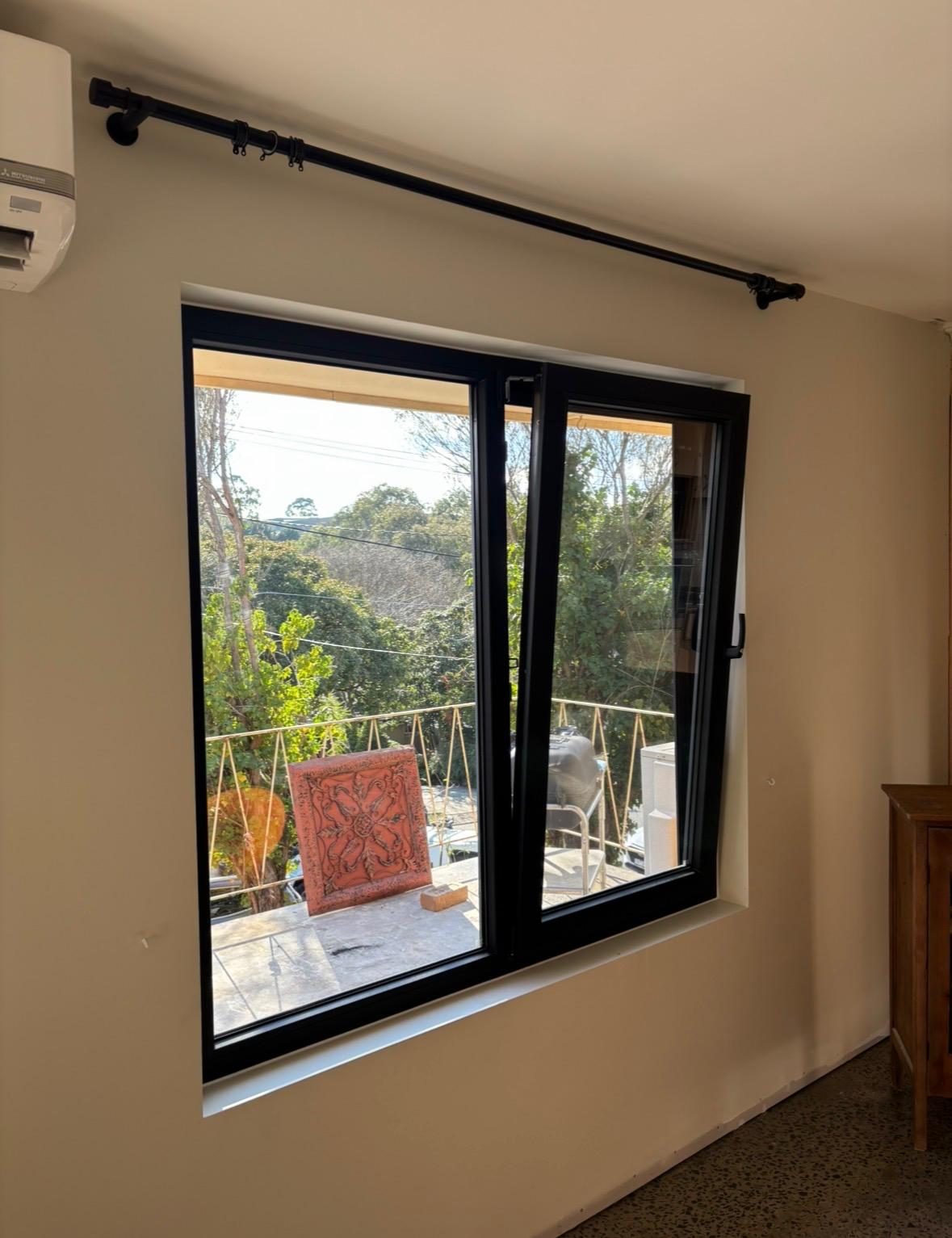 Black uPVC sliding window with hillside outlook